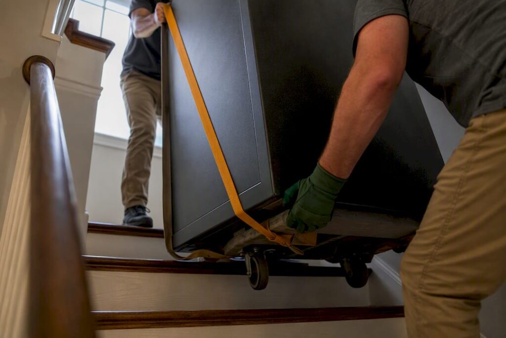 Movers guiding a heavy safe on stairs
