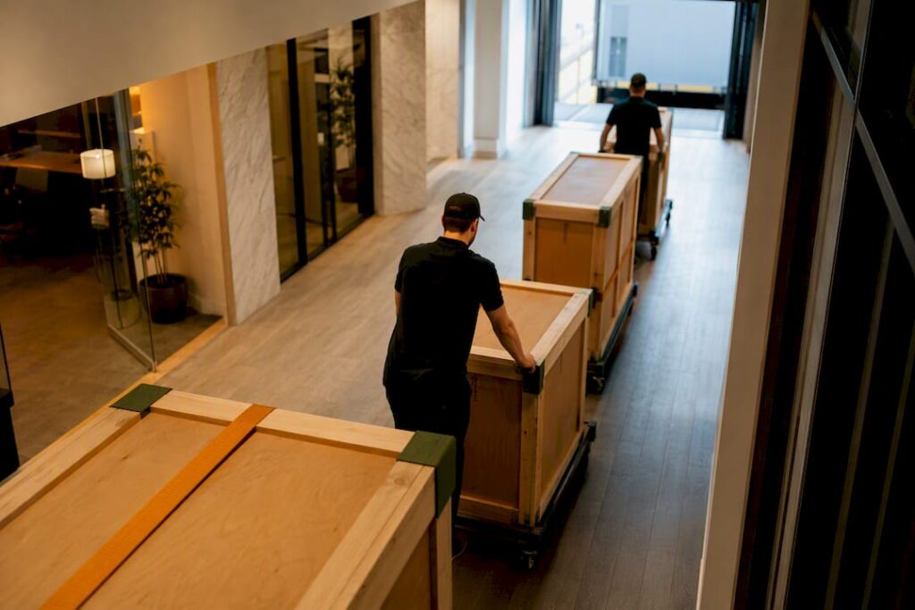 Movers rolling crates through empty office
